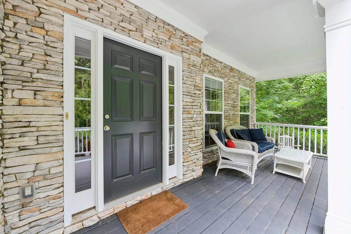 Covered front entry with stone walls, a wood door, and seating